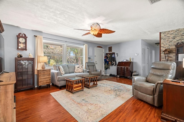 living room featuring ceiling fan, dark wood-type flooring, and a textured ceiling