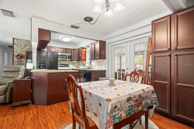 dining space with wood-type flooring, sink, a notable chandelier, crown molding, and french doors