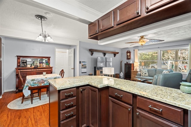 kitchen featuring pendant lighting, wood-type flooring, light stone counters, and a textured ceiling