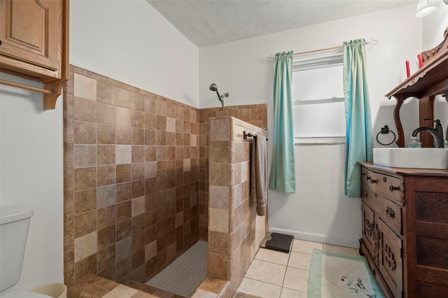 bathroom with tiled shower, vanity, tile patterned flooring, and a textured ceiling