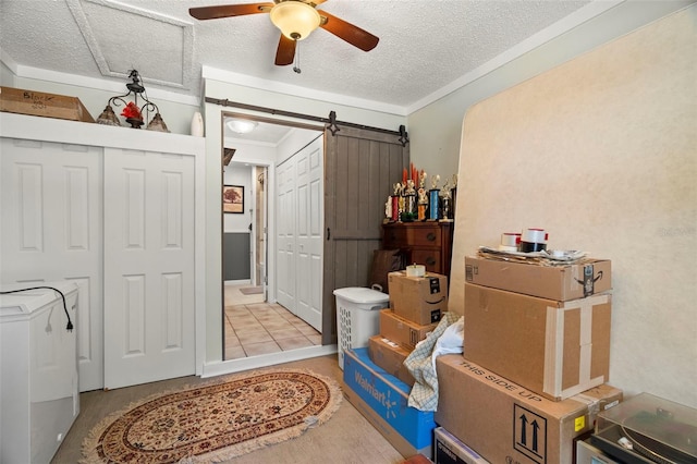 interior space with washer / dryer, ornamental molding, ceiling fan, a barn door, and a textured ceiling