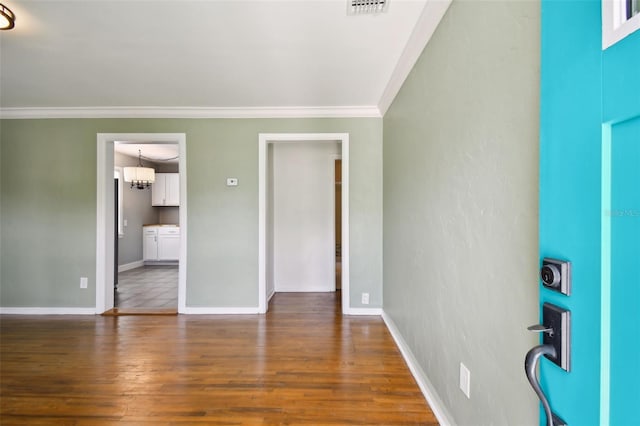 empty room with a chandelier, dark hardwood / wood-style floors, and crown molding