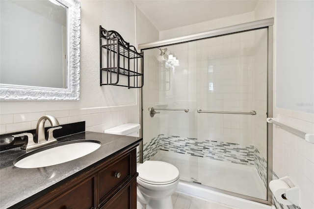 bathroom featuring vanity, toilet, an enclosed shower, and tile walls