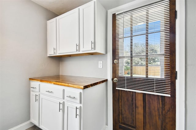 kitchen featuring butcher block countertops and white cabinetry