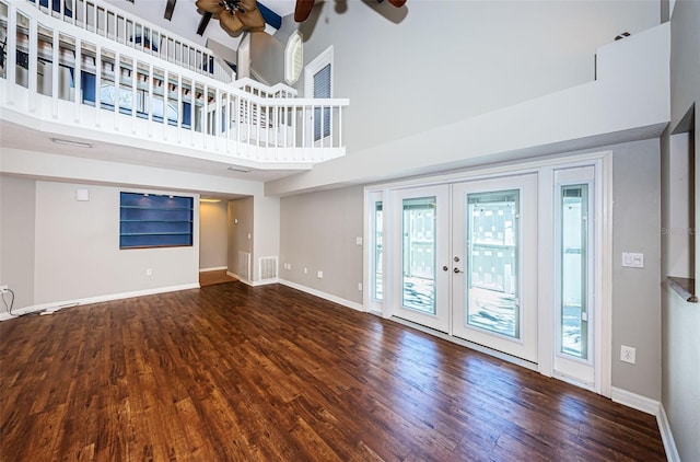 unfurnished living room featuring ceiling fan, french doors, plenty of natural light, a towering ceiling, and hardwood / wood-style flooring