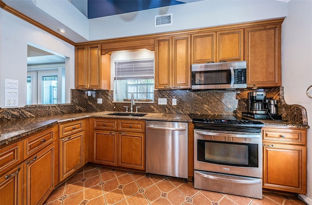 kitchen featuring dark stone counters, sink, tile patterned flooring, decorative backsplash, and stainless steel appliances