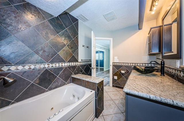 bathroom with tile patterned flooring, vanity, a textured ceiling, and tile walls