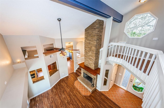 living room with ceiling fan, high vaulted ceiling, beamed ceiling, a fireplace, and hardwood / wood-style floors