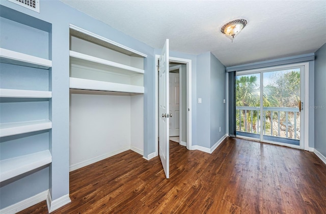 unfurnished bedroom featuring a textured ceiling, a closet, and dark wood-type flooring