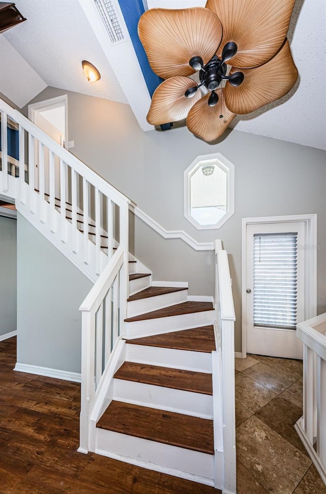 stairway with a textured ceiling, ceiling fan, and lofted ceiling