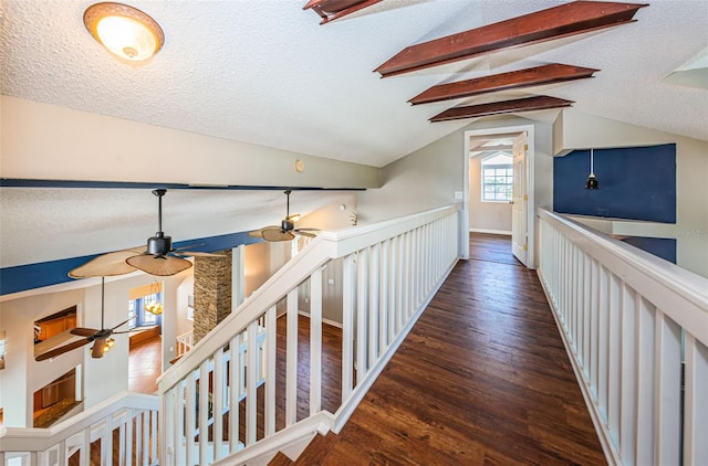 hall featuring lofted ceiling with beams, dark hardwood / wood-style flooring, and a textured ceiling