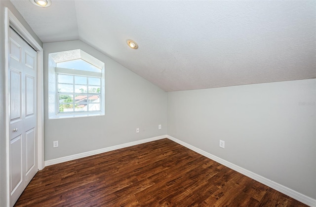 bonus room with dark hardwood / wood-style flooring, lofted ceiling, and a textured ceiling