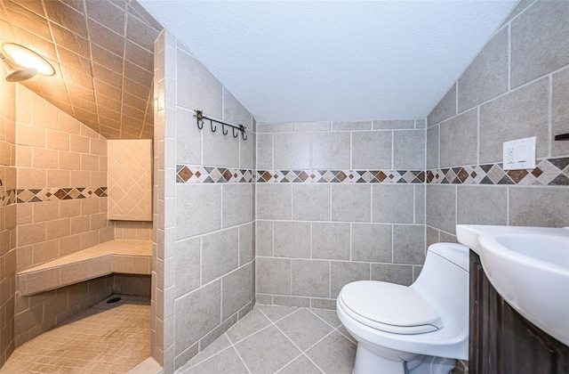 bathroom featuring a shower, tile walls, tile patterned flooring, toilet, and lofted ceiling