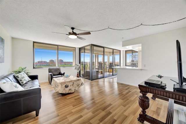 living room with ceiling fan, light hardwood / wood-style floors, and a textured ceiling