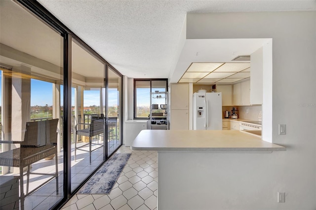 kitchen featuring floor to ceiling windows, white cabinets, white fridge with ice dispenser, a textured ceiling, and kitchen peninsula