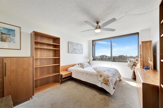 bedroom featuring light carpet, a textured ceiling, and ceiling fan