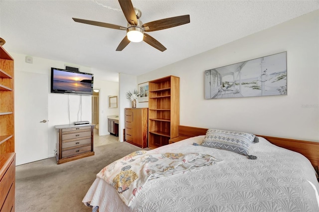 carpeted bedroom with ensuite bathroom, ceiling fan, and a textured ceiling