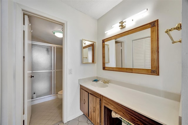 bathroom with tile patterned floors, a textured ceiling, vanity, toilet, and a shower with shower door