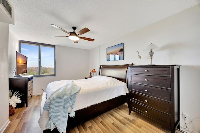 bedroom featuring ceiling fan, light hardwood / wood-style flooring, and a textured ceiling