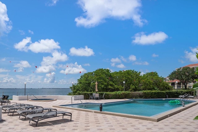 view of pool with a water view and a patio area