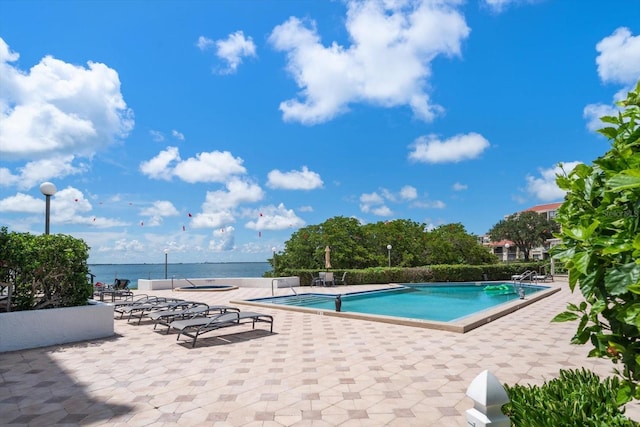 view of swimming pool featuring a patio area and a water view