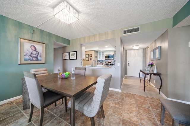 dining area featuring an inviting chandelier, tile patterned floors, and a textured ceiling