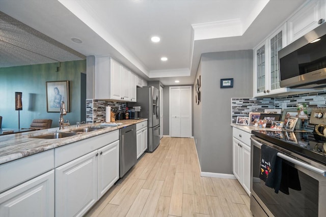 kitchen featuring sink, stainless steel appliances, light hardwood / wood-style floors, light stone countertops, and white cabinets