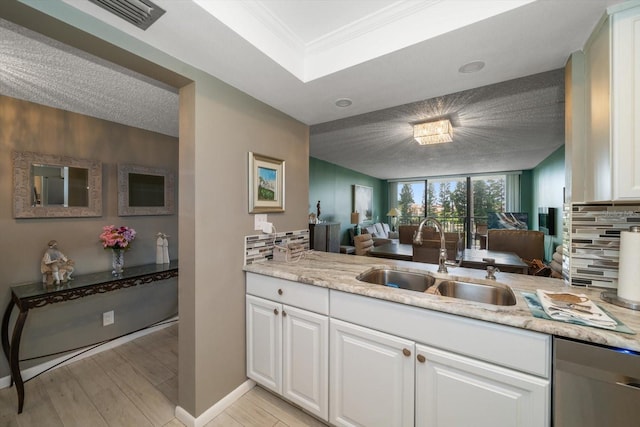 kitchen featuring sink, white cabinetry, light hardwood / wood-style flooring, stainless steel dishwasher, and backsplash