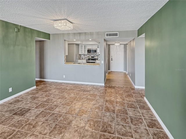 unfurnished living room featuring tile patterned flooring, sink, and a textured ceiling