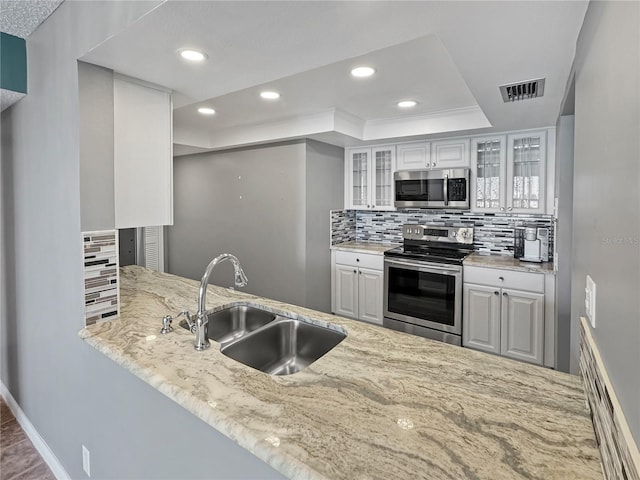 kitchen featuring a raised ceiling, tasteful backsplash, sink, white cabinets, and stainless steel appliances