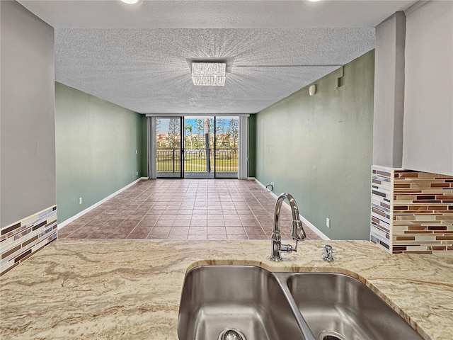 kitchen with sink, tile patterned flooring, floor to ceiling windows, a textured ceiling, and decorative backsplash