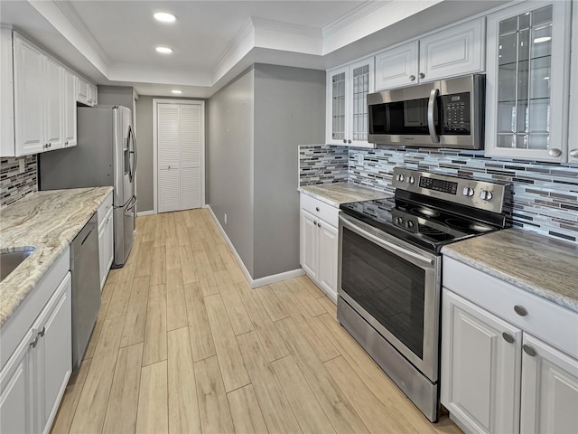 kitchen with white cabinetry, a tray ceiling, ornamental molding, and stainless steel appliances