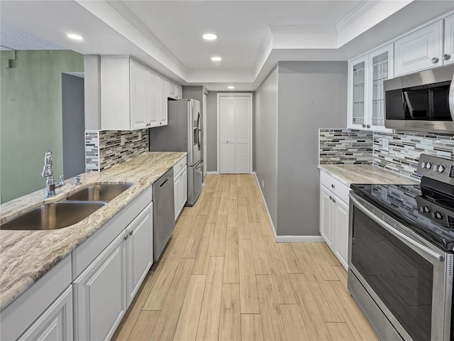 kitchen featuring appliances with stainless steel finishes, white cabinetry, sink, light stone counters, and light hardwood / wood-style floors