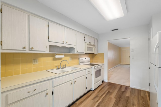 kitchen featuring hardwood / wood-style flooring, backsplash, white appliances, and sink