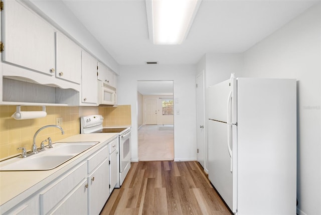 kitchen with decorative backsplash, light wood-type flooring, white appliances, sink, and white cabinets