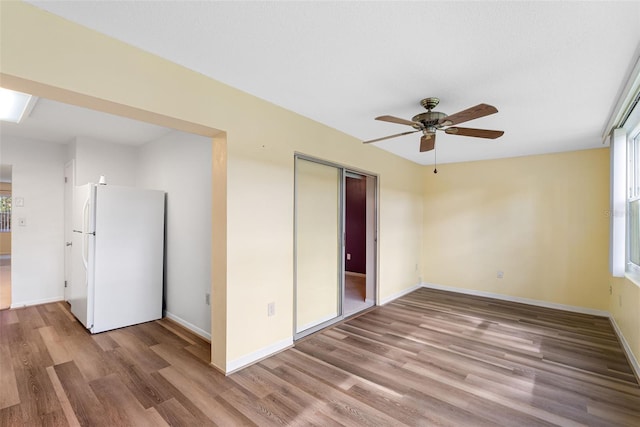 unfurnished bedroom with light wood-type flooring, white refrigerator, a closet, and ceiling fan