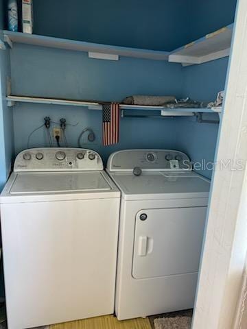 laundry room featuring washing machine and clothes dryer and light hardwood / wood-style flooring