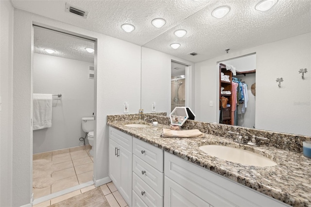 bathroom with vanity, toilet, tile patterned flooring, and a textured ceiling