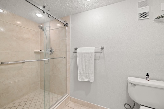 bathroom featuring a textured ceiling, toilet, walk in shower, and tile patterned flooring