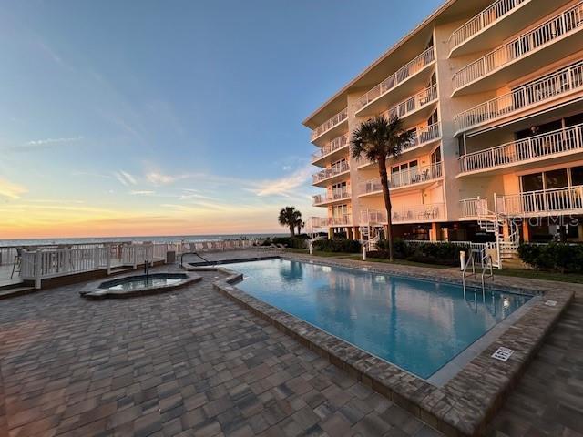 pool at dusk featuring a community hot tub and a patio