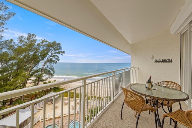 balcony with a water view and a view of the beach