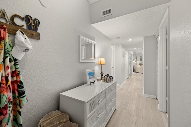 hallway featuring a textured ceiling and light hardwood / wood-style floors