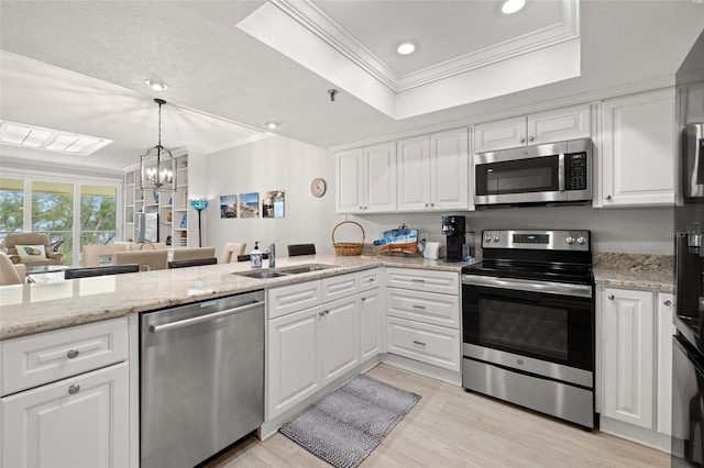 kitchen with an inviting chandelier, appliances with stainless steel finishes, a tray ceiling, white cabinets, and sink