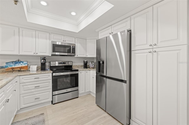 kitchen featuring white cabinetry, a tray ceiling, stainless steel appliances, and crown molding