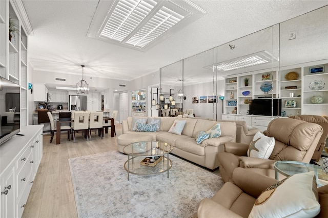 living room featuring an inviting chandelier, a textured ceiling, and light wood-type flooring