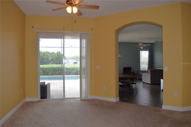 empty room with ceiling fan, plenty of natural light, and dark carpet