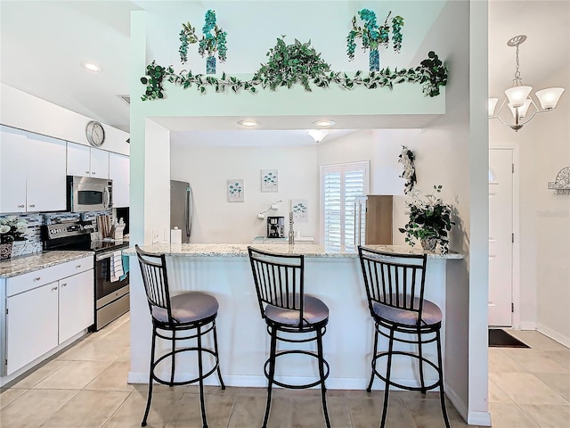 kitchen with appliances with stainless steel finishes, tasteful backsplash, white cabinetry, and decorative light fixtures