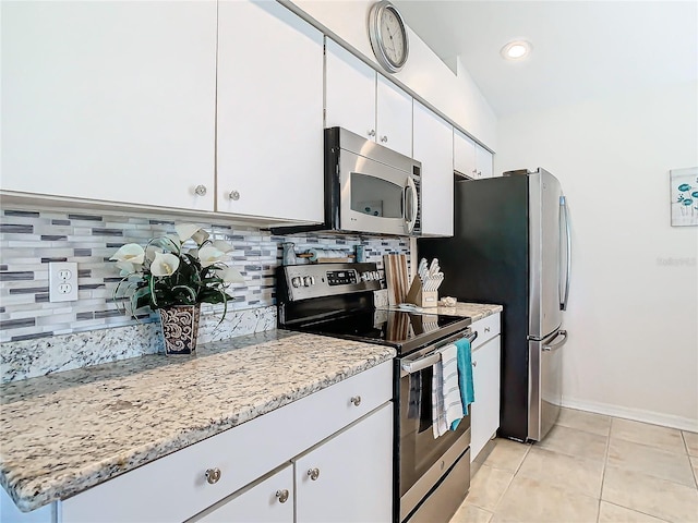 kitchen with tasteful backsplash, light stone counters, stainless steel appliances, light tile patterned floors, and white cabinets