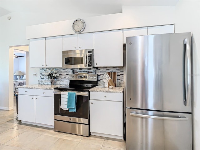 kitchen featuring vaulted ceiling, white cabinets, stainless steel appliances, and light tile patterned floors