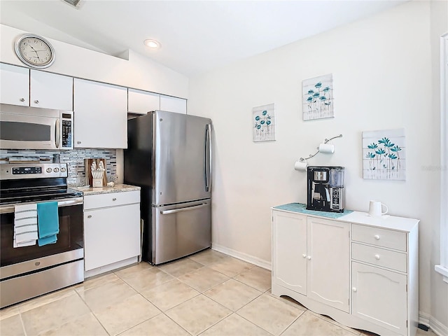 kitchen with vaulted ceiling, decorative backsplash, light tile patterned floors, white cabinetry, and stainless steel appliances